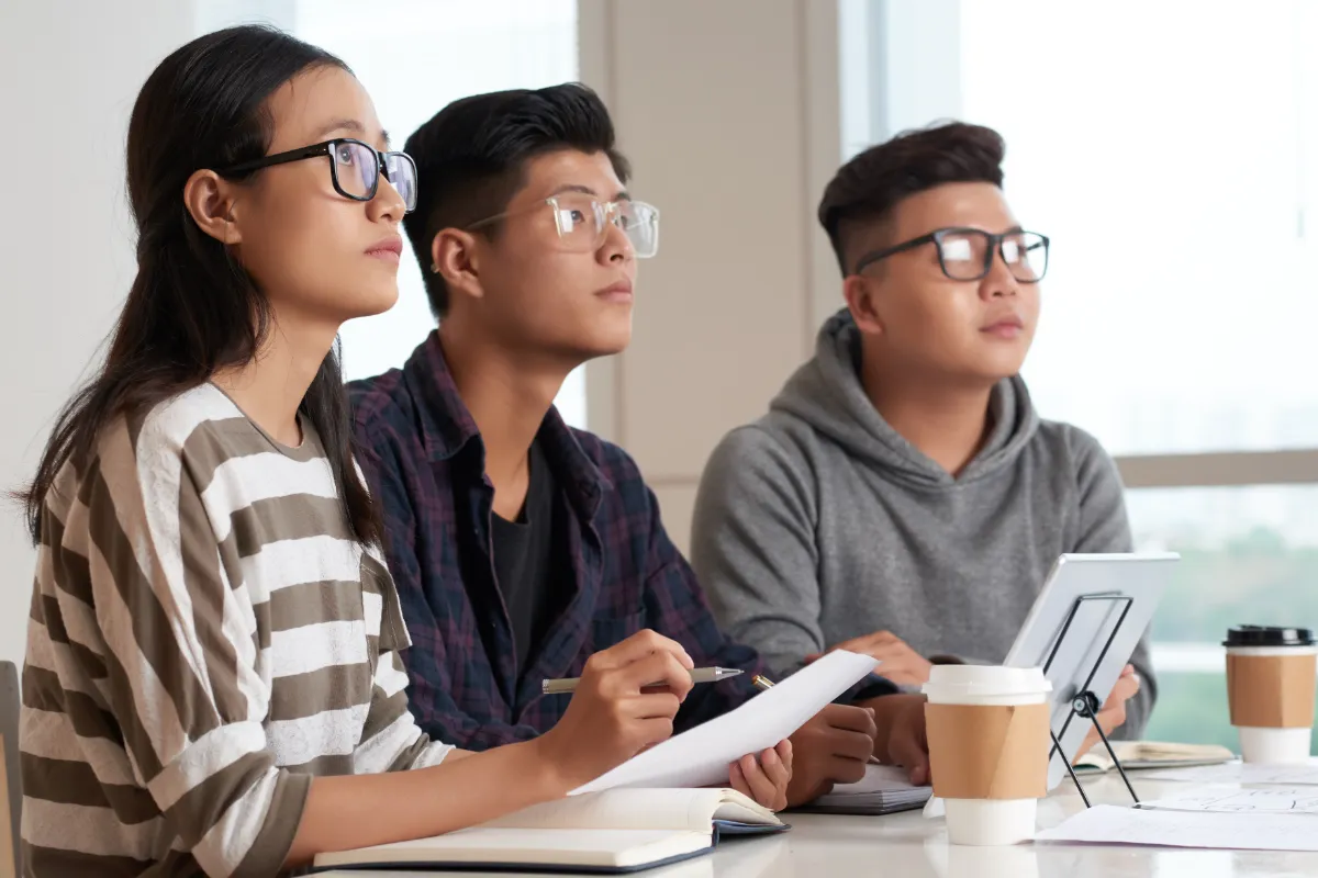 A group of Asian secondary school students engaged in an active classroom discussion in Singapore