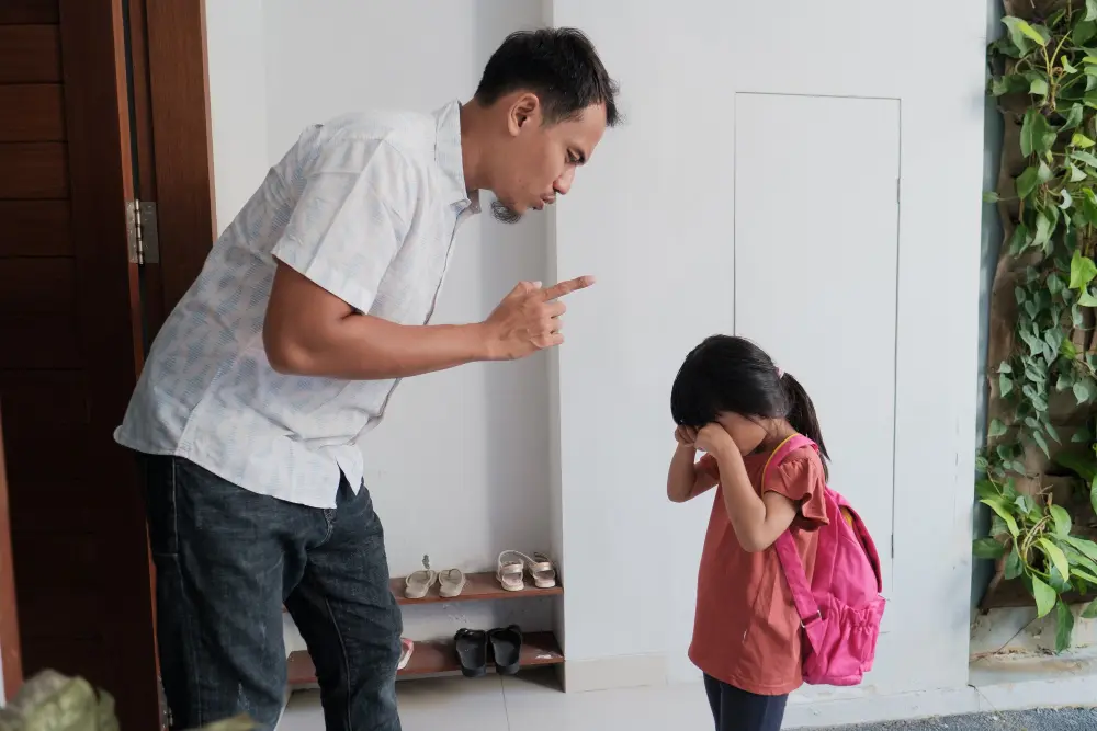 A father looks upset and reprimanding his crying daughter