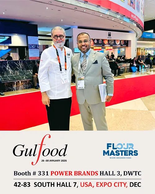 Two men posing at Gulfood 2026 expo; one in chef coat, the other in gray suit holding documents.