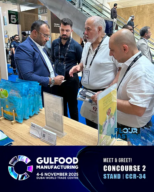 Four men in conversation at a trade show booth with blue product packaging and promotional signs.