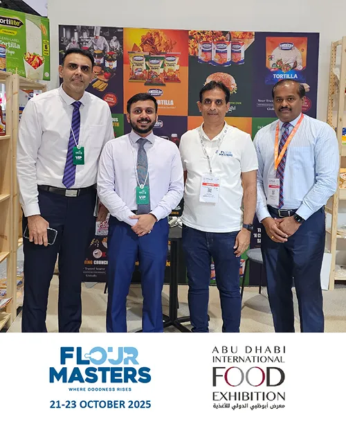 Four men standing in front of a Flour Masters and Abu Dhabi International Food Exhibition banner.