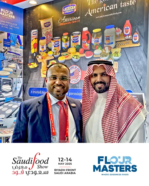 Two men smiling at a trade show booth with American Specialty Foods products and Flour Masters branding.