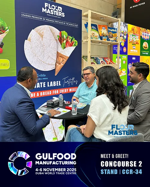 Four people seated at a table discussing near Flour Masters tortilla display at Gulfood Manufacturing 2025.