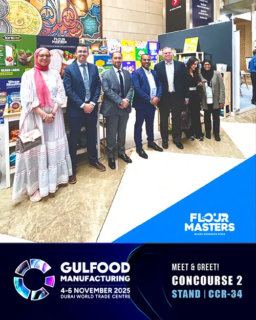 Seven people smiling and posing at a Flour Masters booth at Gulfood Manufacturing Dubai event.