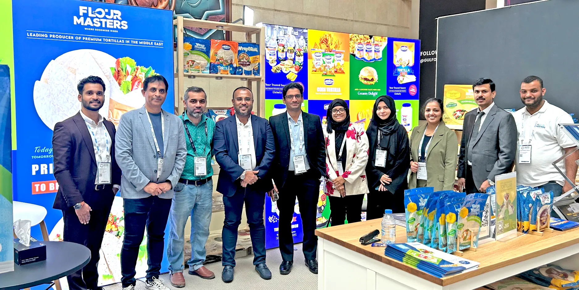Group of ten professionals posing at a trade show booth for Flour Masters tortilla products.
