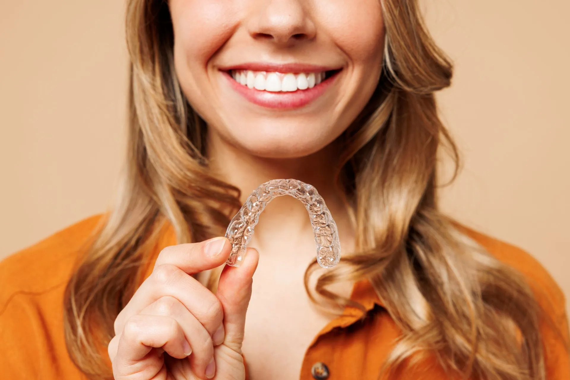 Patient holding clear Invisalign aligner trays used for orthodontic treatment at Nova Dental Care of Chantilly