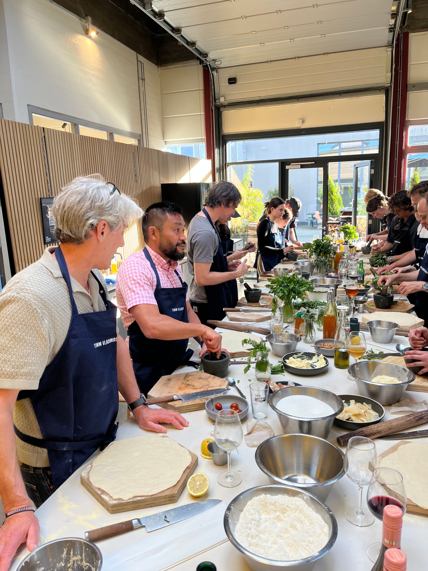 The Aegir Insights team rolling pizza dough and grinding pesto at a long prep table