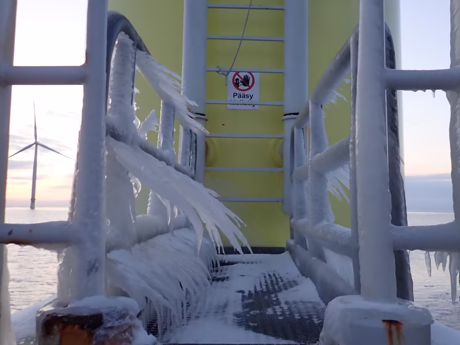 Picture of a Finnish wind farm, covered in ice. In the background one can see an offshore wind turbine.