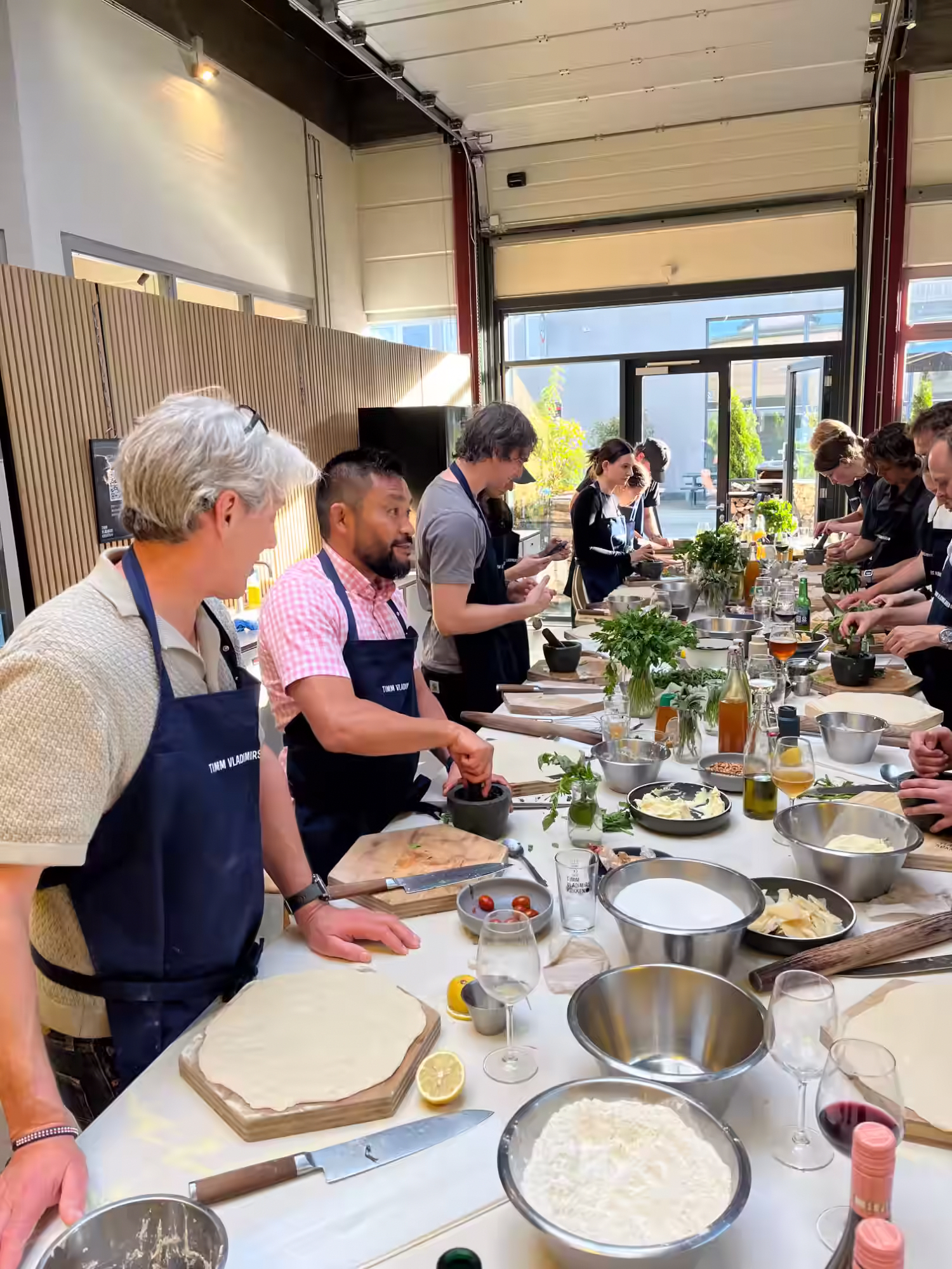 The Aegir Insights team rolling pizza dough and grinding pesto at a long prep table