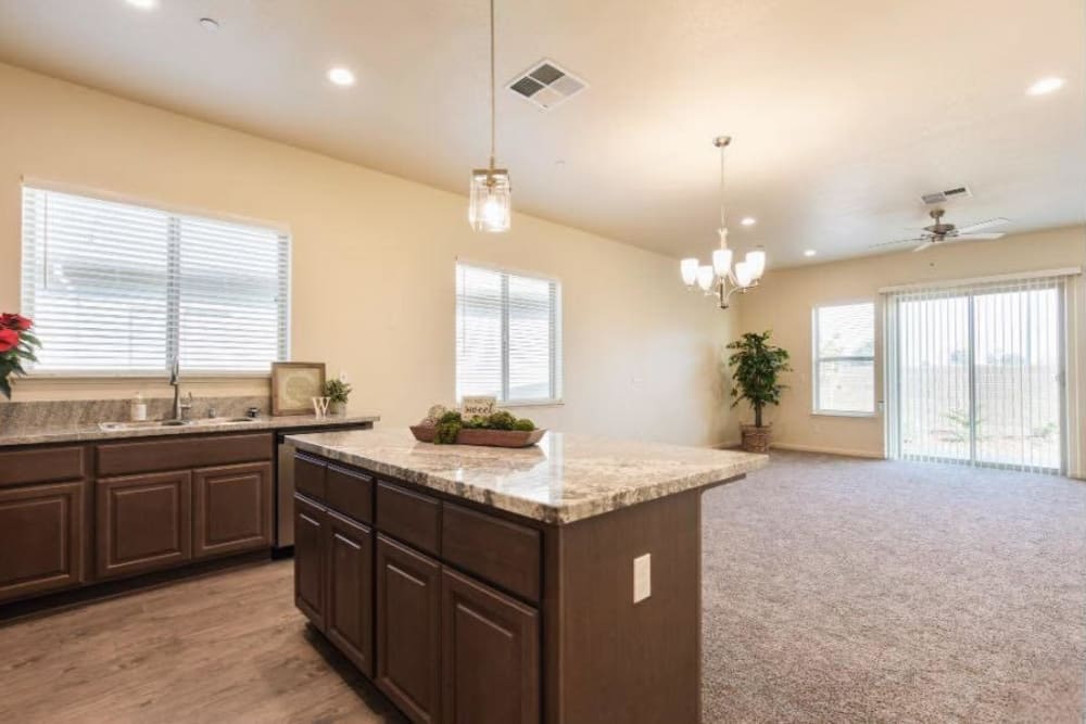 Kitchen island with brown cabinets and view of unfurnished living area with carpet and patio sliding doors