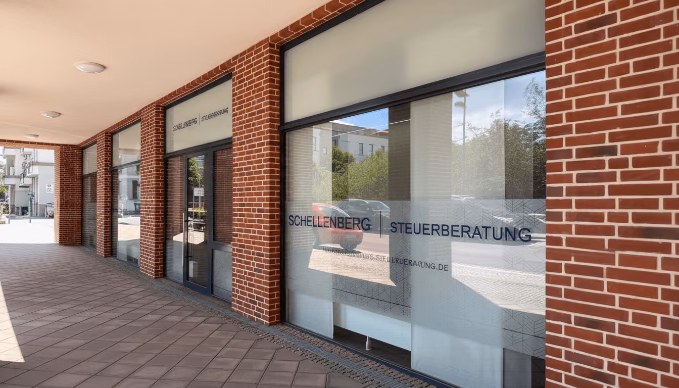 Fenster und Eingang eines roten Backsteingebäudes mit den Büroräumen der Schellenberg Steuerberatung.