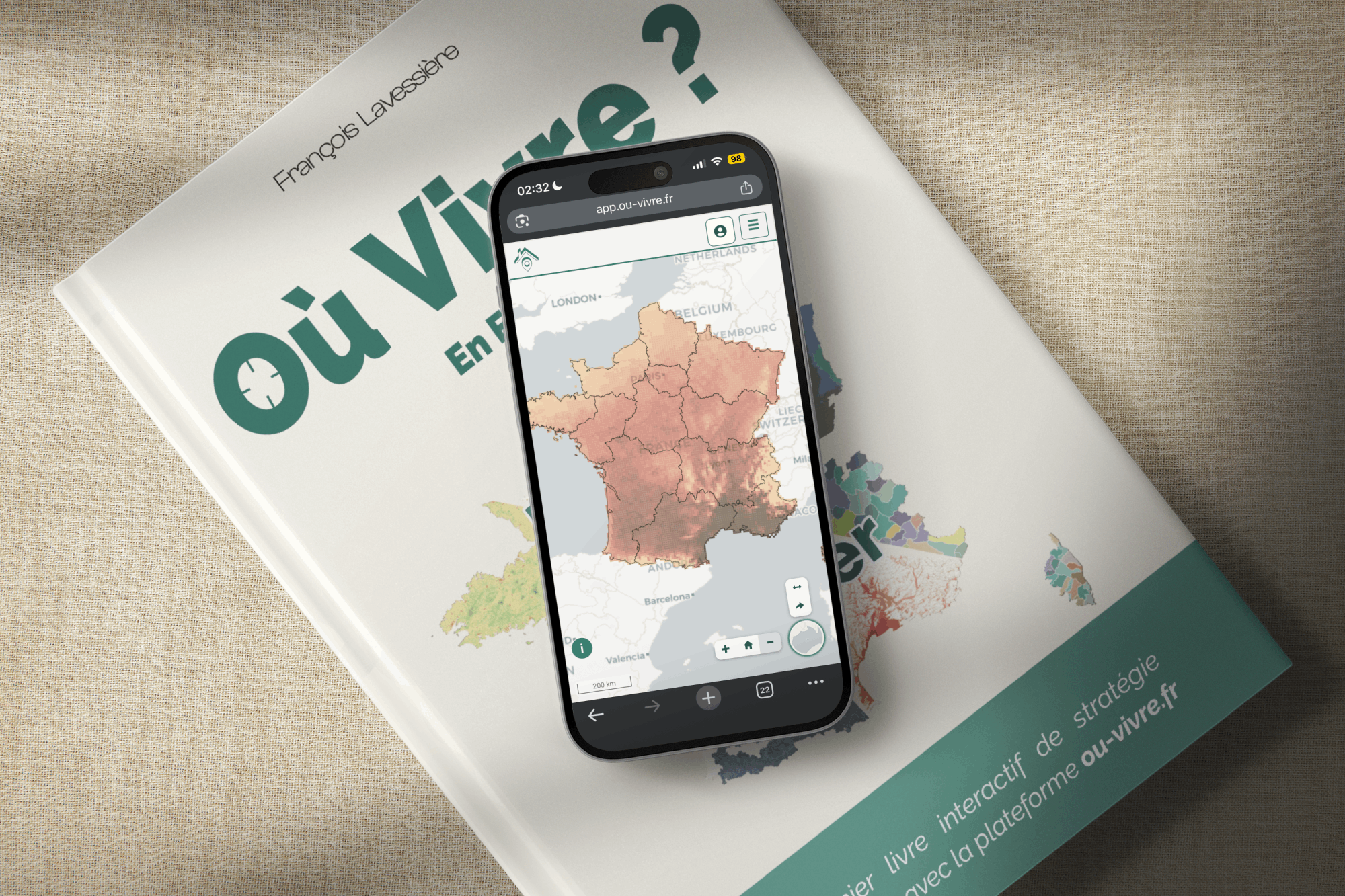 Le livre Où Vivre ? posé, avec un smartphone affichant l'application interactive de cartographie