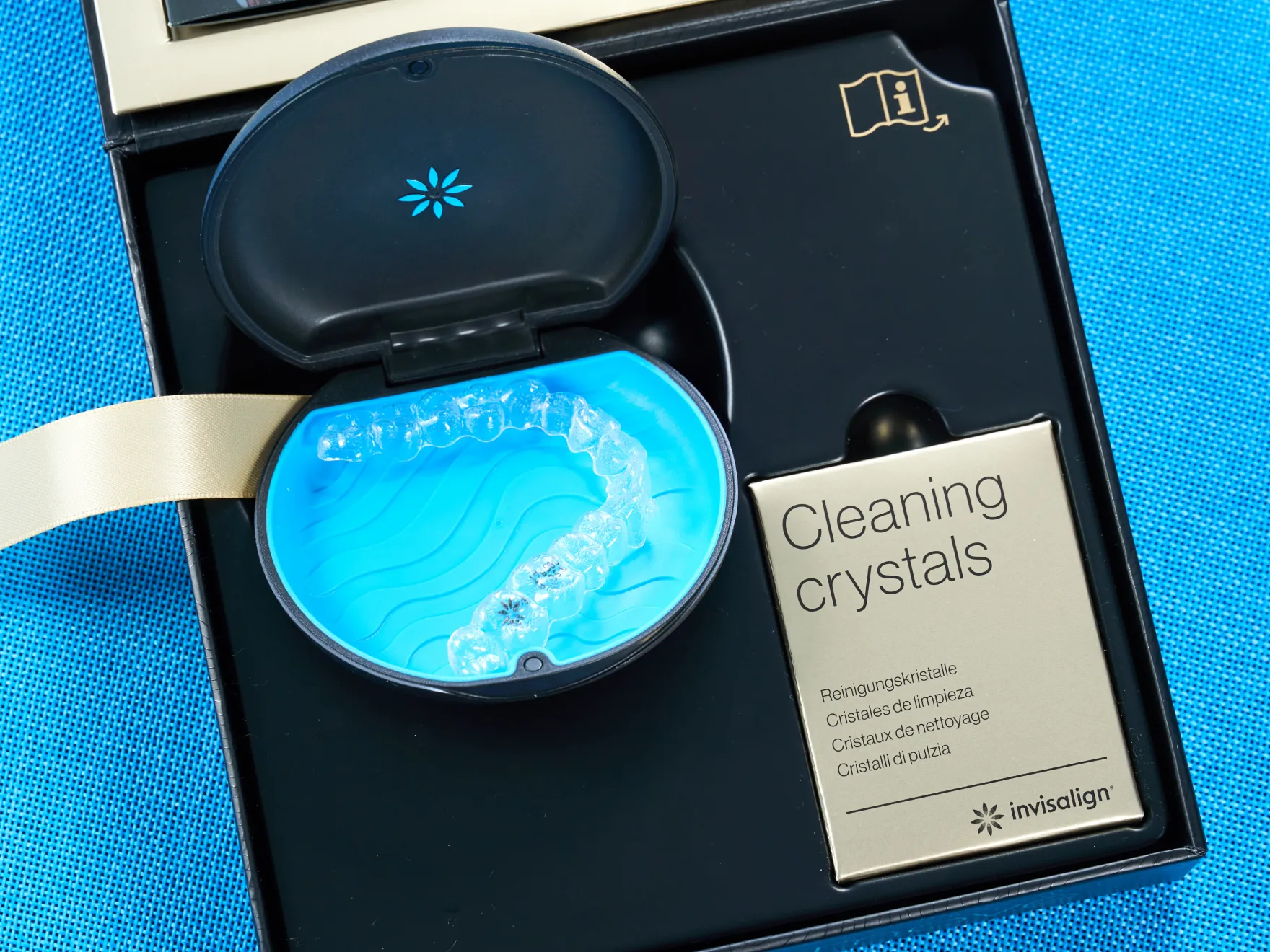 Clear Invisalign aligner in black and blue case with box of cleaning crystals in packaging.