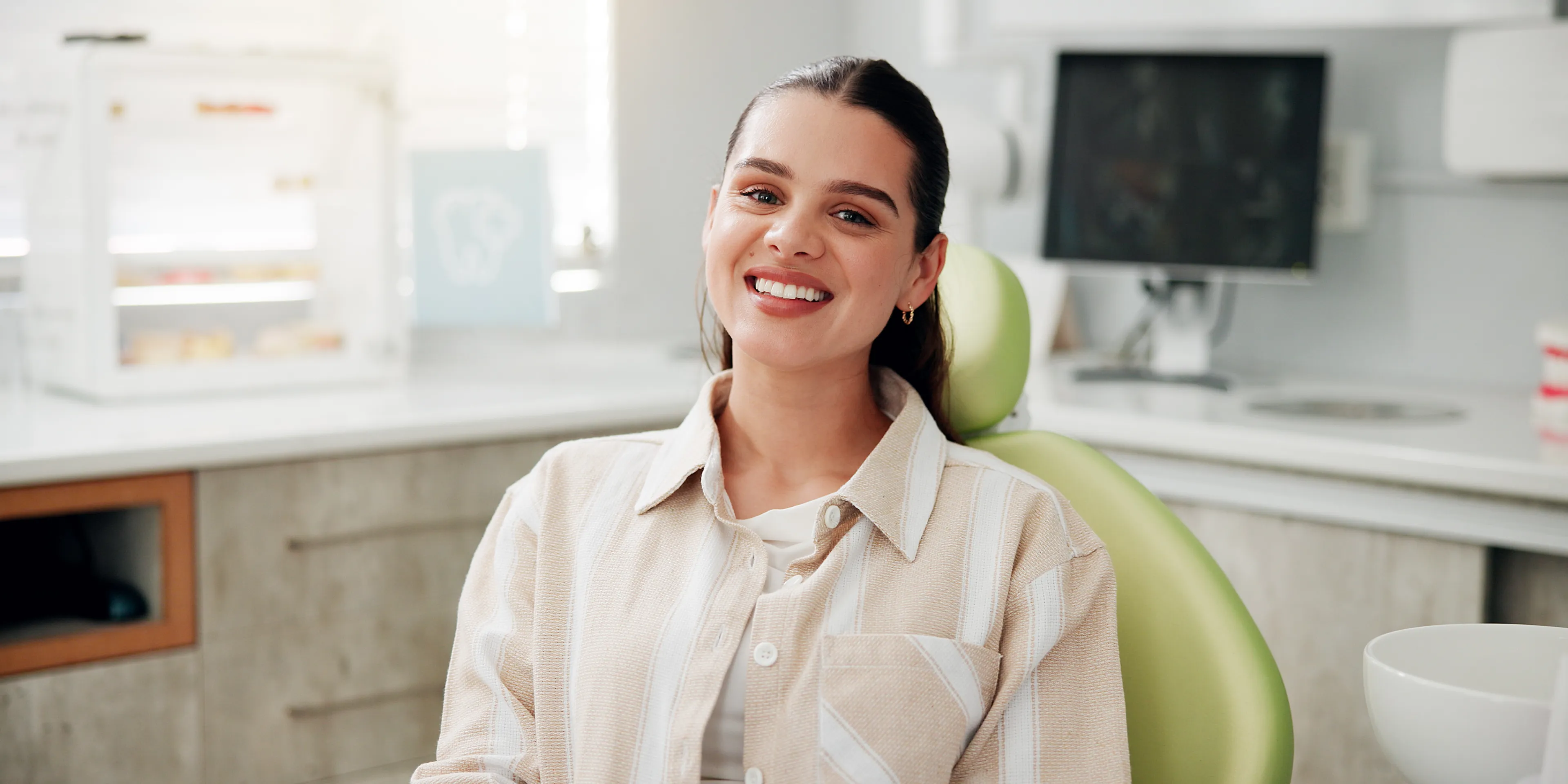 Smiling woman seated in a dental office chair with a bright, white smile.
