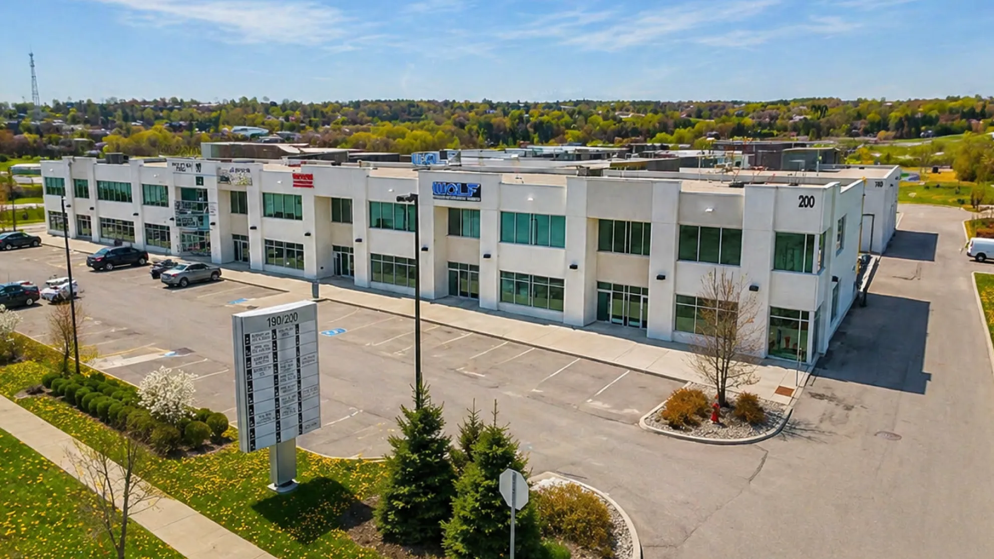 Two-story commercial building with parking lot and a directory sign on a sunny day.
