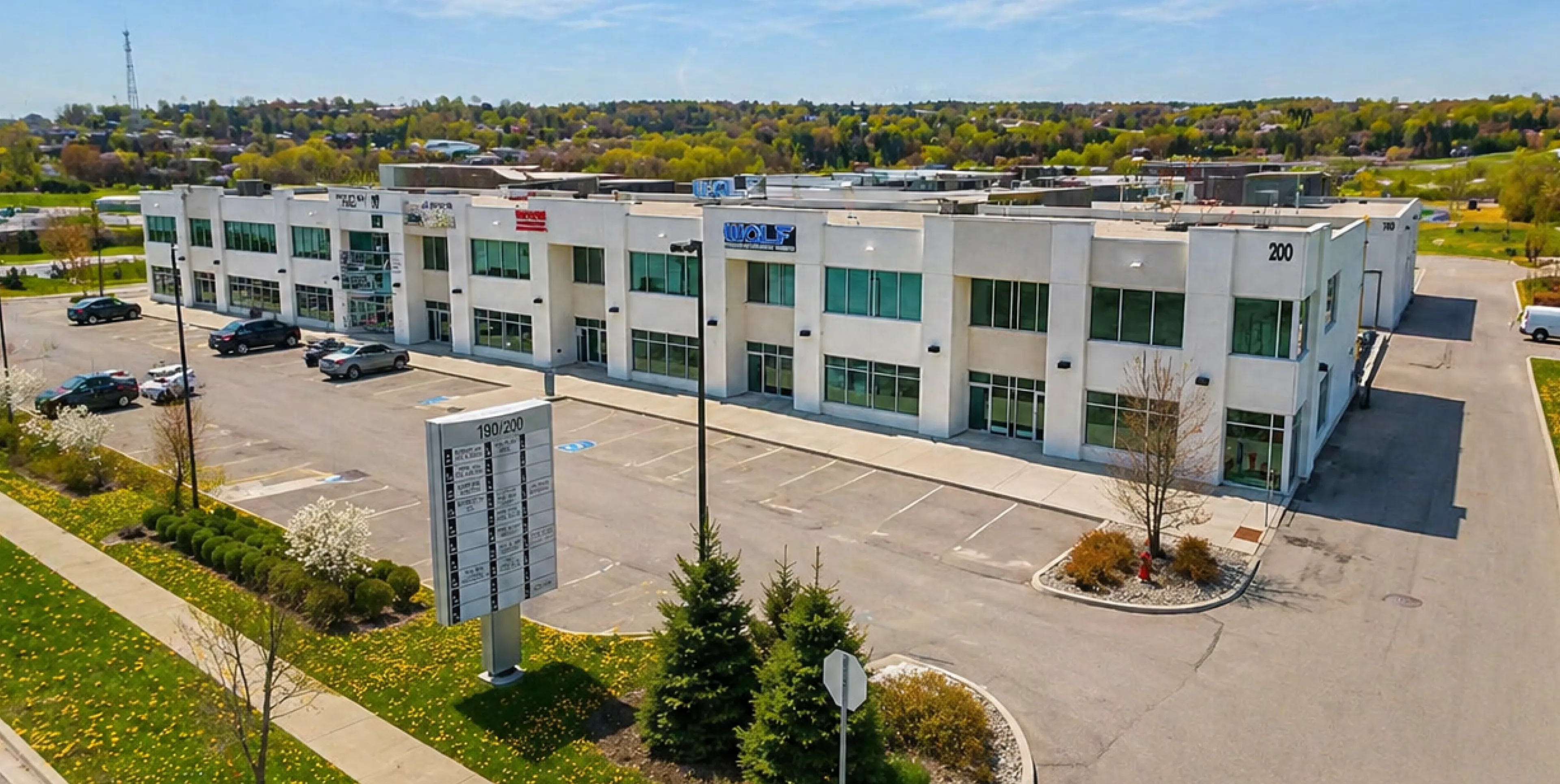 Two-story commercial building with large windows and adjacent parking lot under a clear sky.