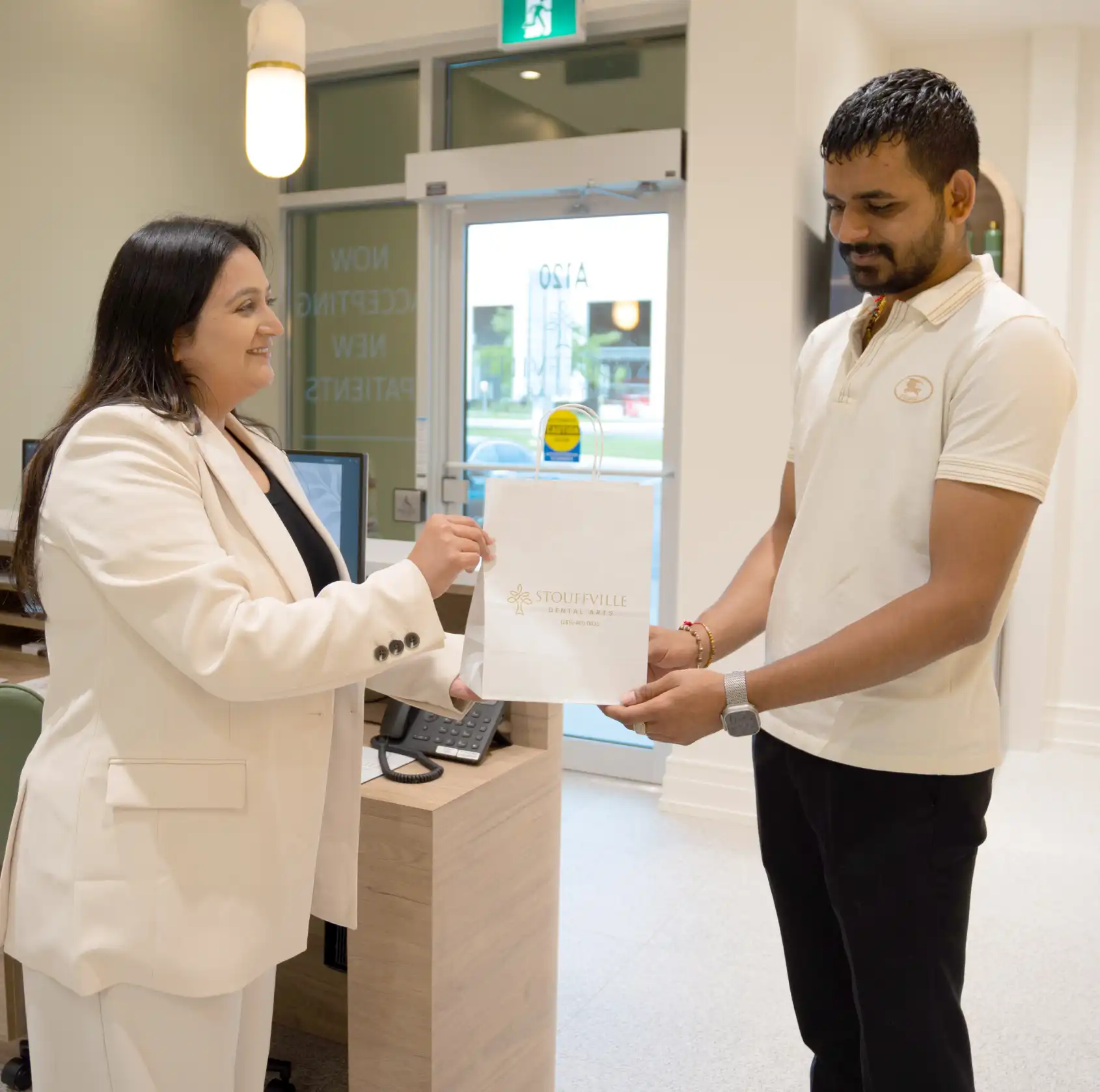 Stouffville Dental Arts team member giving a gift bag to client
