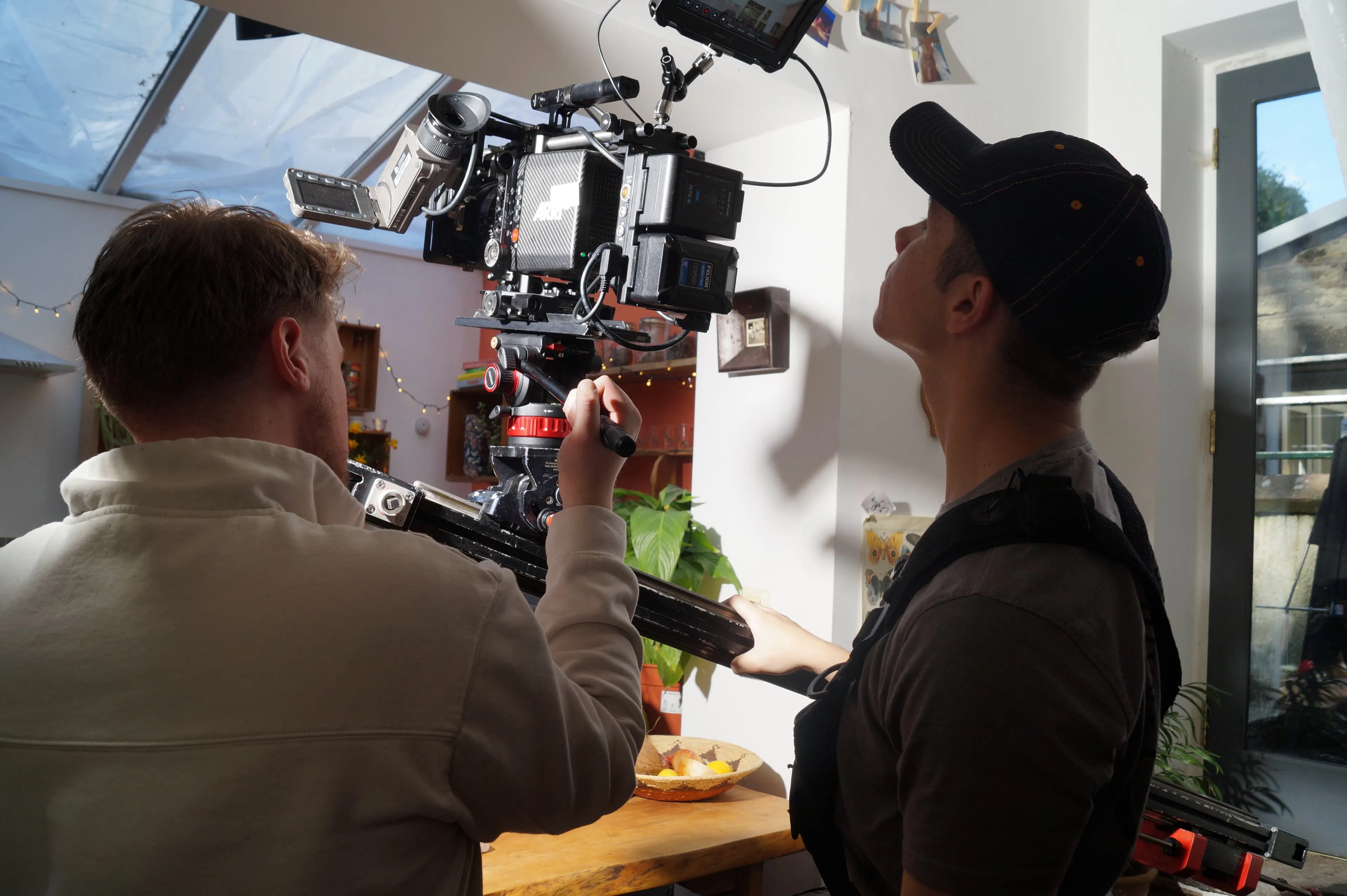 Two team members operate professional-grade video equipment in a bright setting, capturing high-quality footage for charity storytelling content.