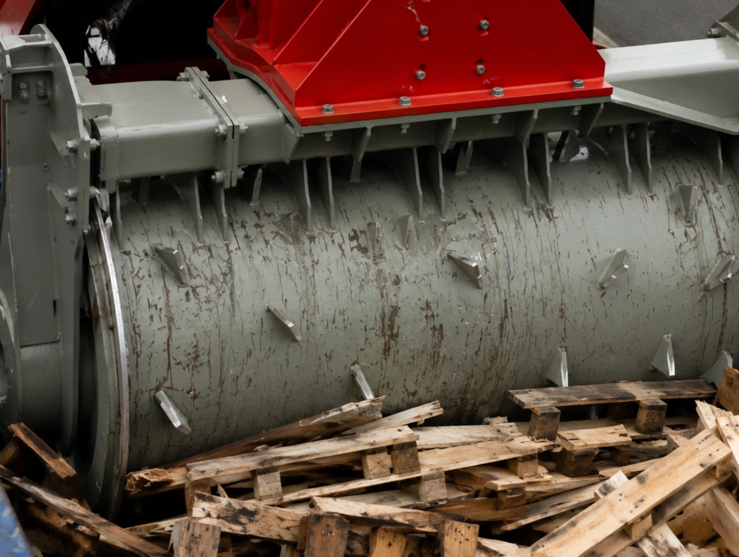Close up of a compaction spiked roller crushing wood inside a dumpster