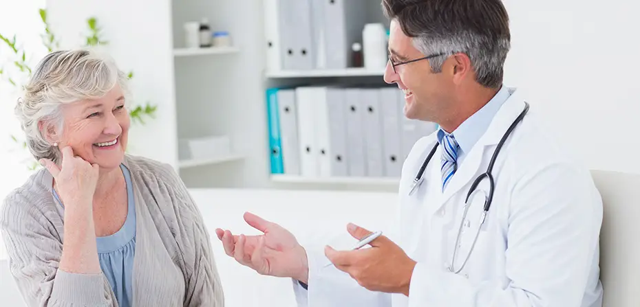 Smiling female patient and male doctor with stethoscope having a friendly discussion in office.