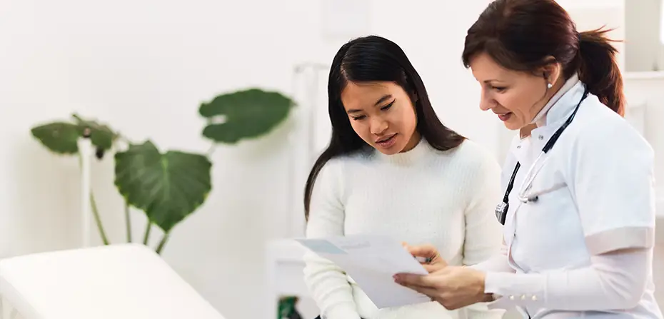 Female doctor explaining medical results to a patient in a bright, modern clinic room.