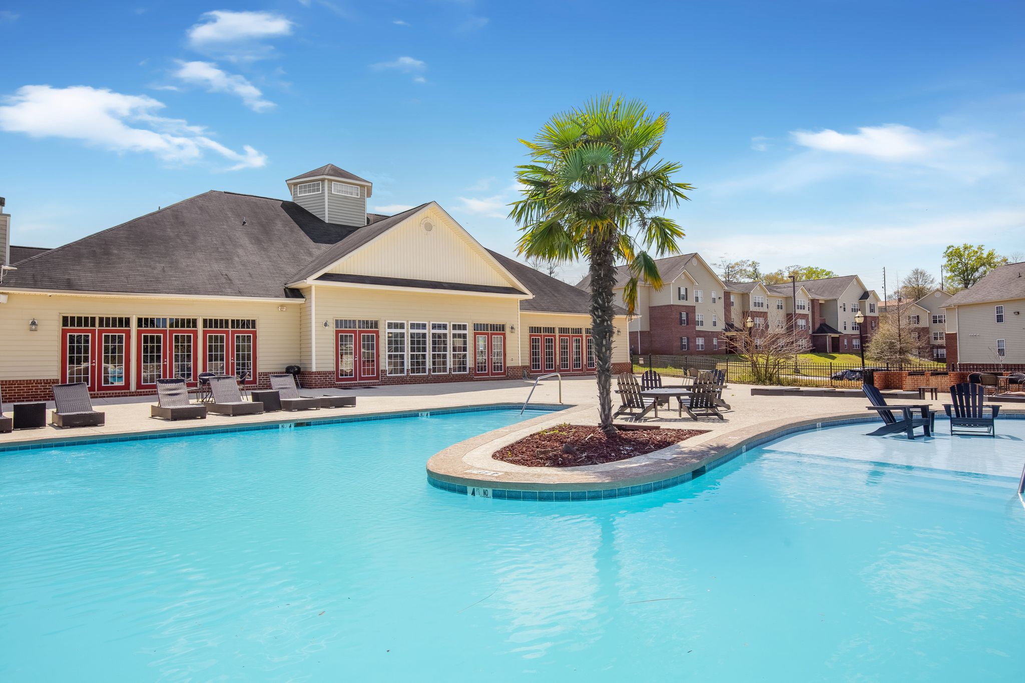 Swimming pool with lounge chairs and palm trees with view of clubhouse