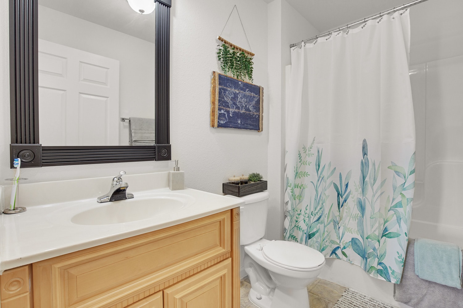 Bathroom with brown cabinets, vanity with mirror and shower bath combo with curtain