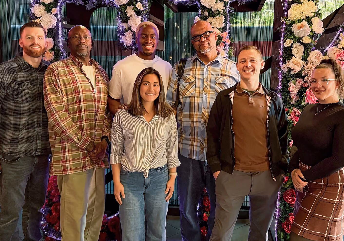 The Checkr.org team smiling indoors in front of floral and light decorations.
