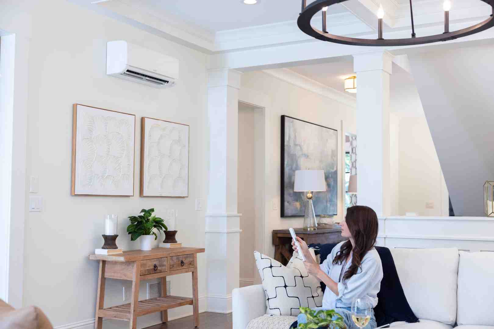 Modern ductless mini-split wall unit mounted in contemporary living room showing sleek design and remote control - hvac draper