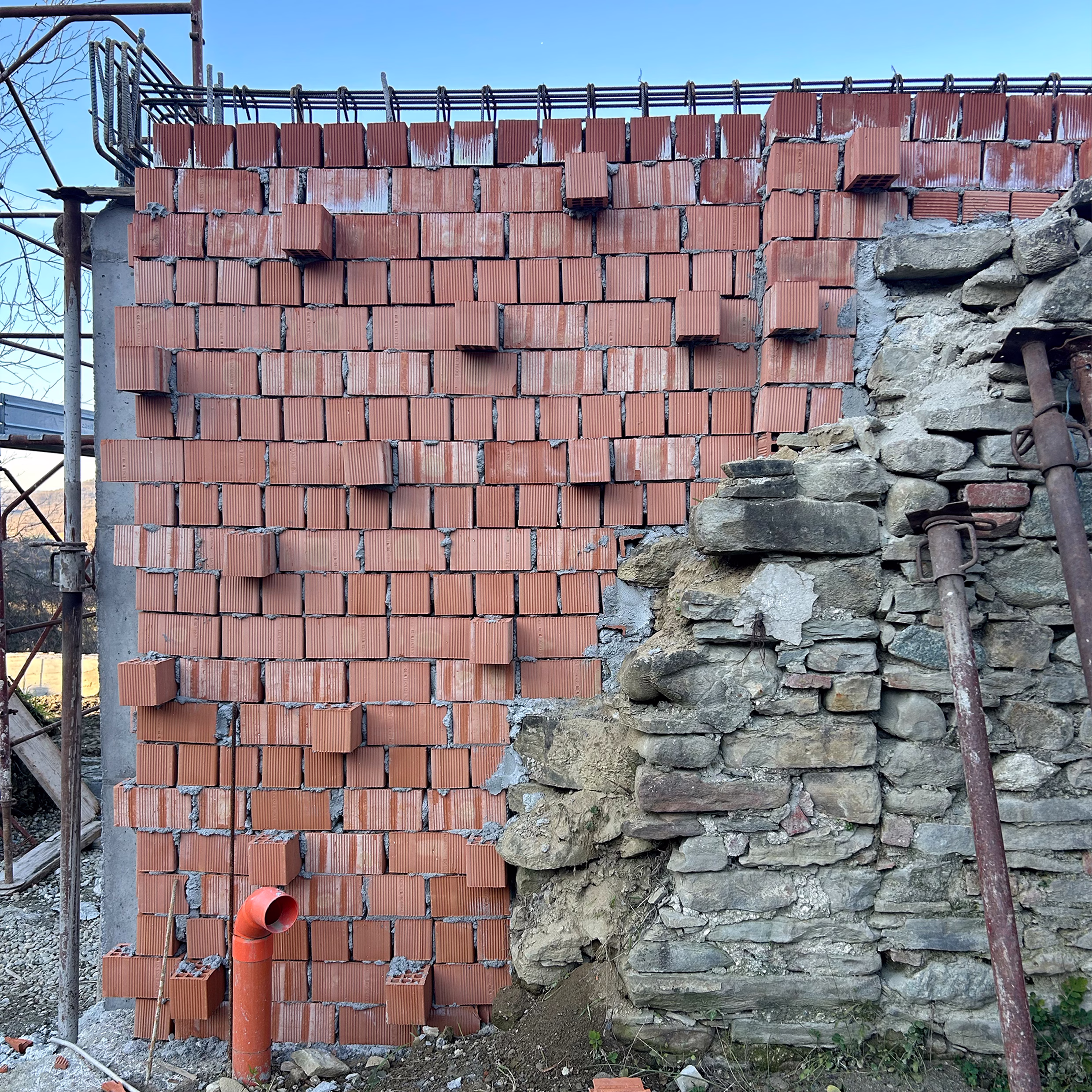 Close-up of a textured brick and exposed stone wall showing construction materials and layering detail