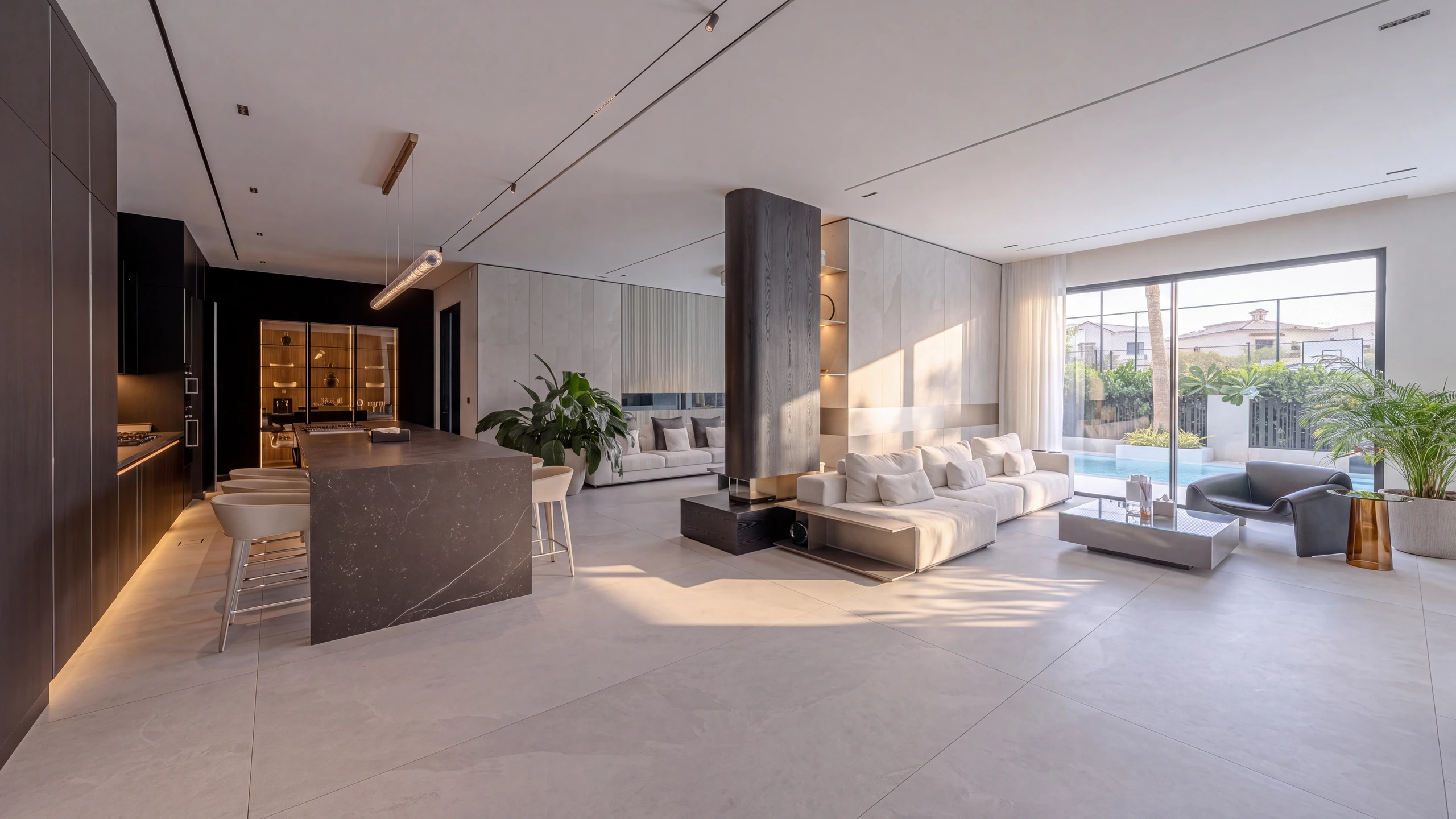 The open-plan living and kitchen space of a completed DMDC house — a stone island, timber panelling and full-height glazing onto the pool terrace