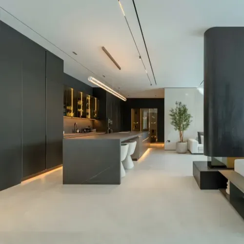 A dark kitchen with brass-lit glazed cabinetry and a stone island