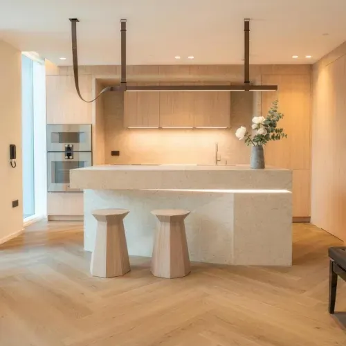 A kitchen with a solid stone island, oak cabinetry and herringbone flooring
