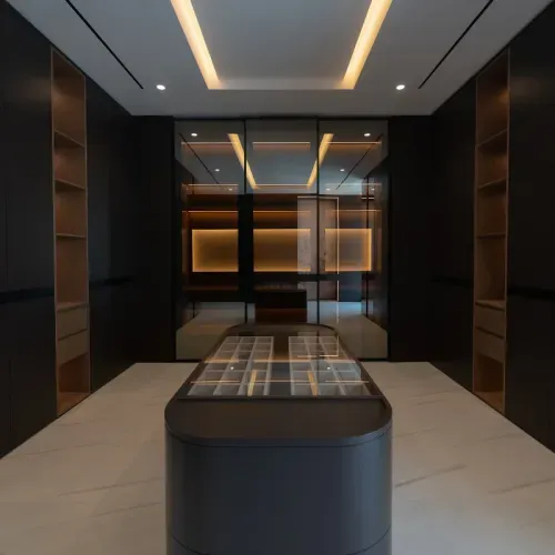 A dressing room with glass-fronted joinery and a lit display island
