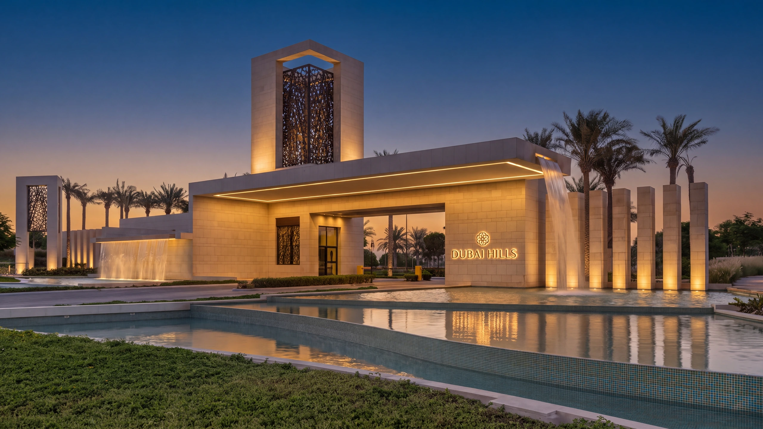 The Dubai Hills entrance gateway at dusk, its waterfall and reflecting pools lit