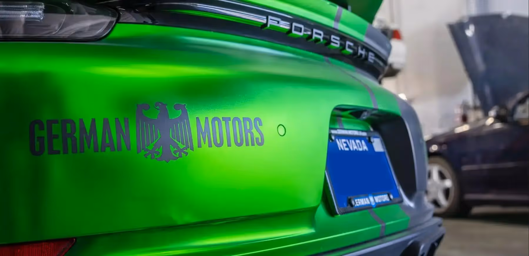 Rear of bright green Porsche with German Motors logo and Nevada license plate in a garage.