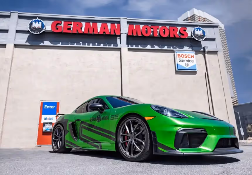 Bright green sports car with black stripes parked in front of a building labeled German Motors and Bosch Service.