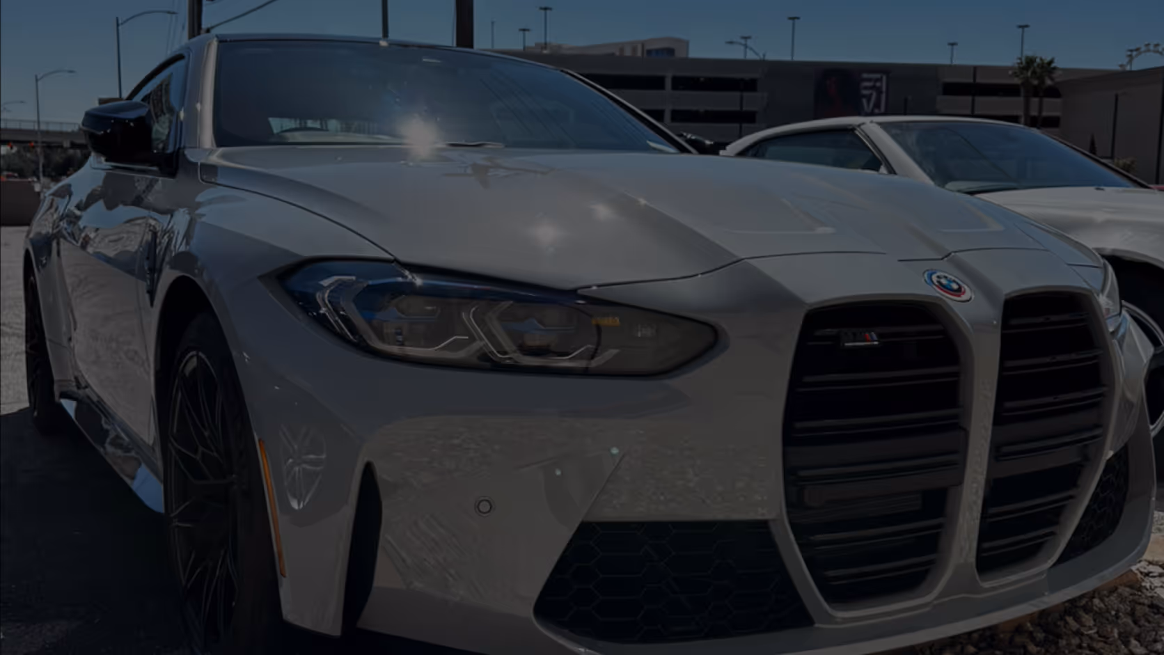 Gray BMW M4 with distinctive large kidney grille and sleek headlights parked outdoors.