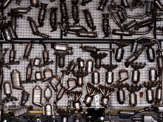 Multiple catalytic converters and exhaust components displayed on a metal grid wall.
