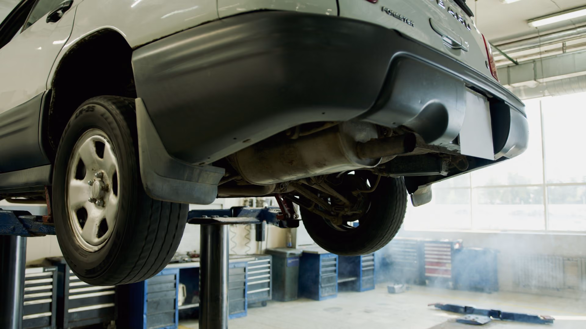 Car elevated on a lift in a garage with rear exhaust system visible under the bumper.