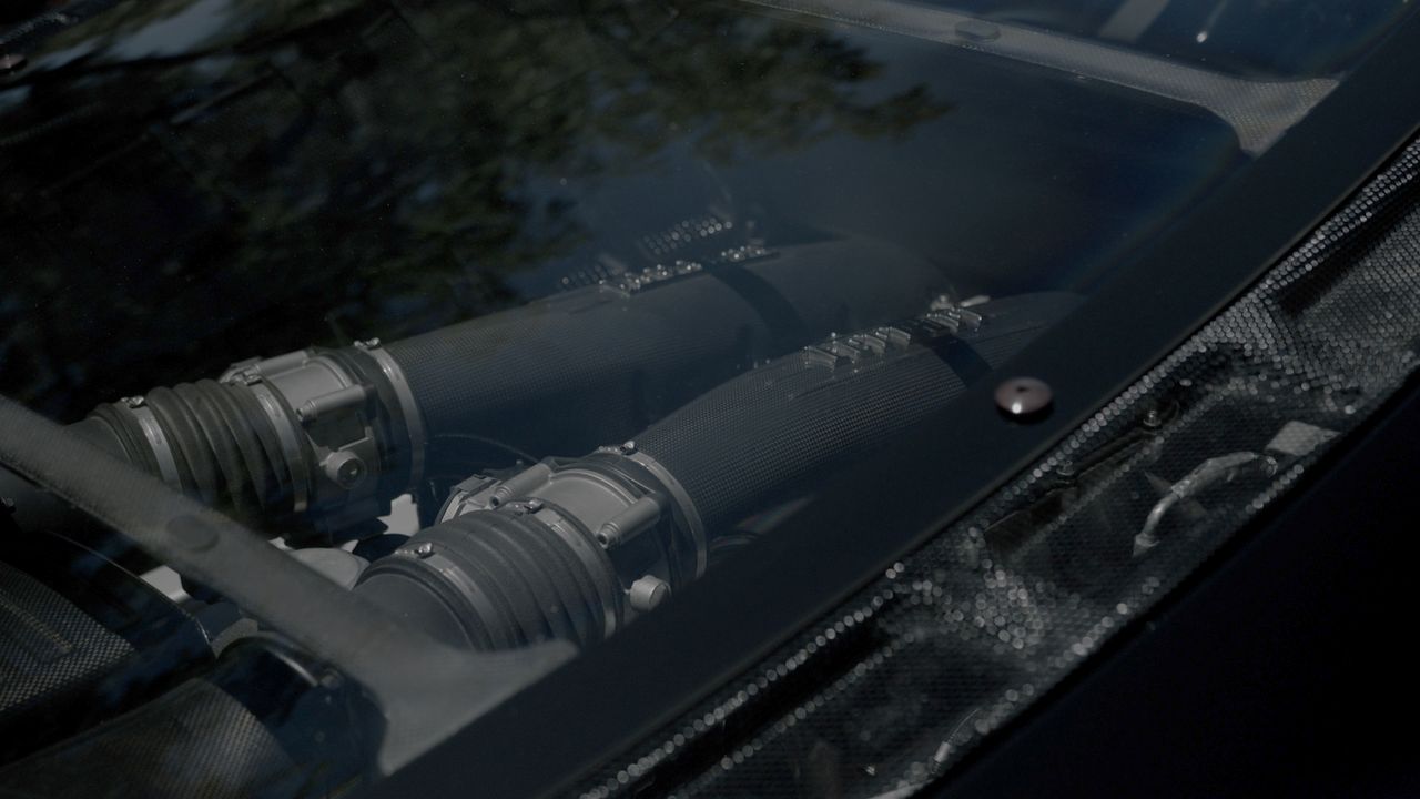 Close-up of a car engine seen through the rear window with carbon fiber details.