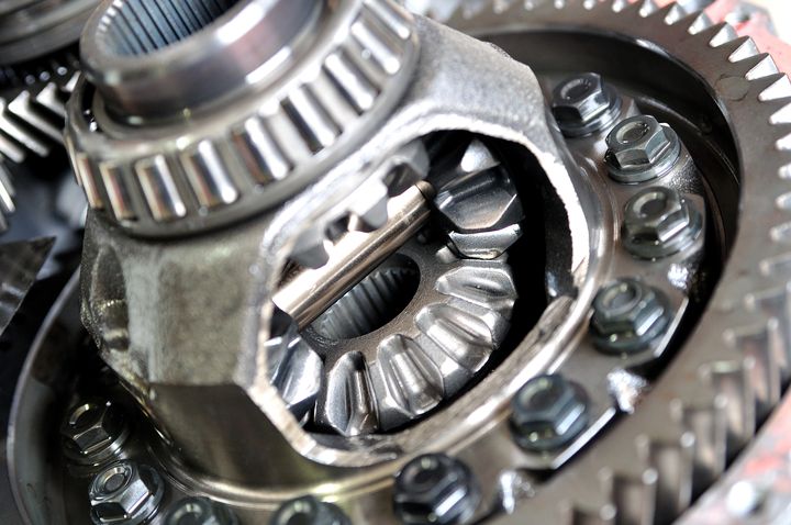 Close-up of shiny metallic gears and bolts inside a mechanical gear assembly.