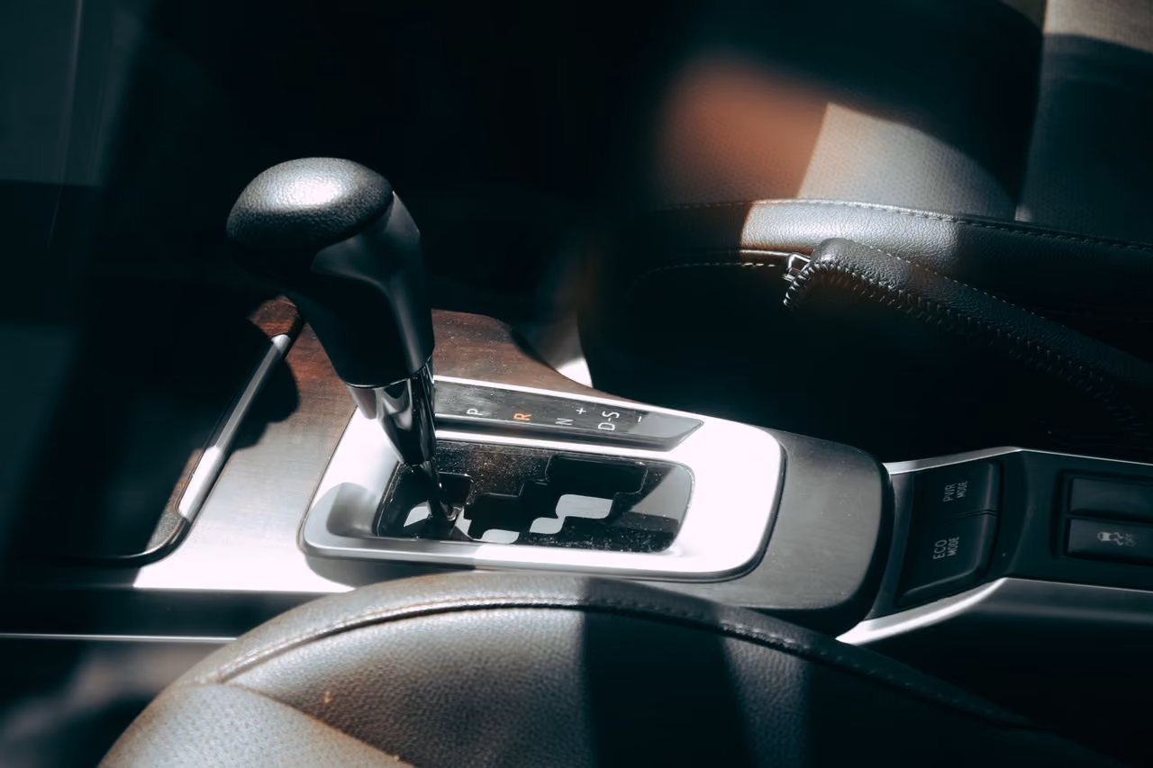 Close-up of a car's automatic gear shift lever and surrounding console with mode buttons.