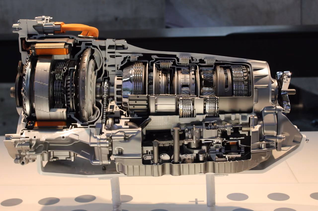Close-up of a metallic car transmission system cutaway showing intricate gears and components.