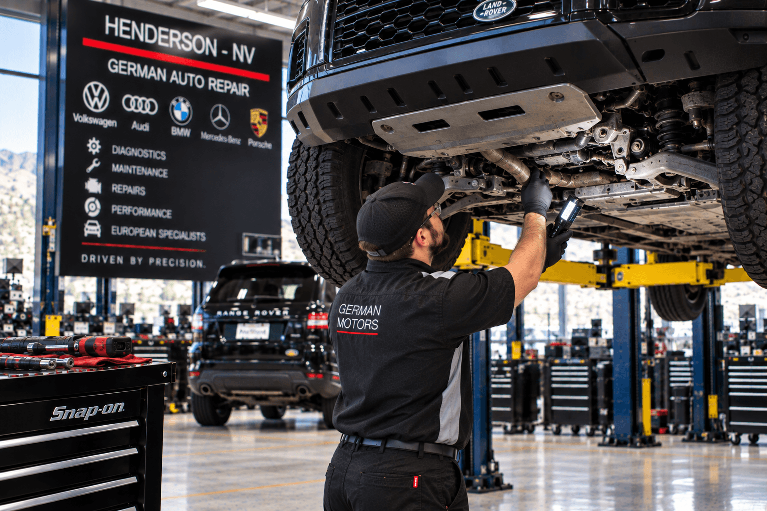 Land Rover Repair in Henderson - NV technician inspecting underbody components on a lifted SUV
