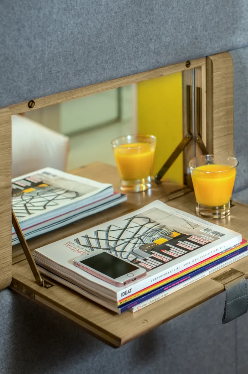 Tablette murale en bois avec magazines, smartphone et jus d'orange dans une chambre Hospitality Family.