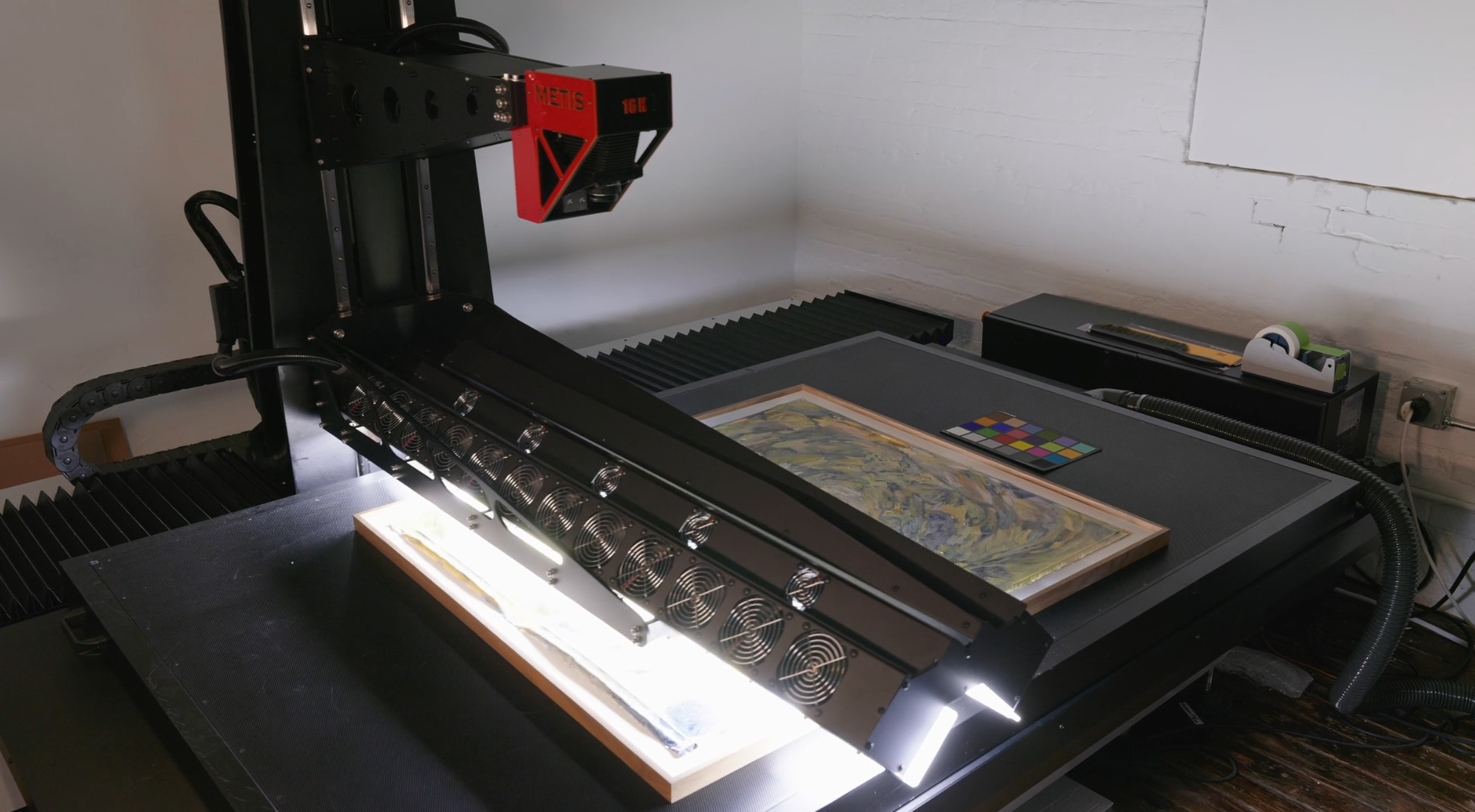 Large flatbed art scanner digitizing framed artwork in a studio