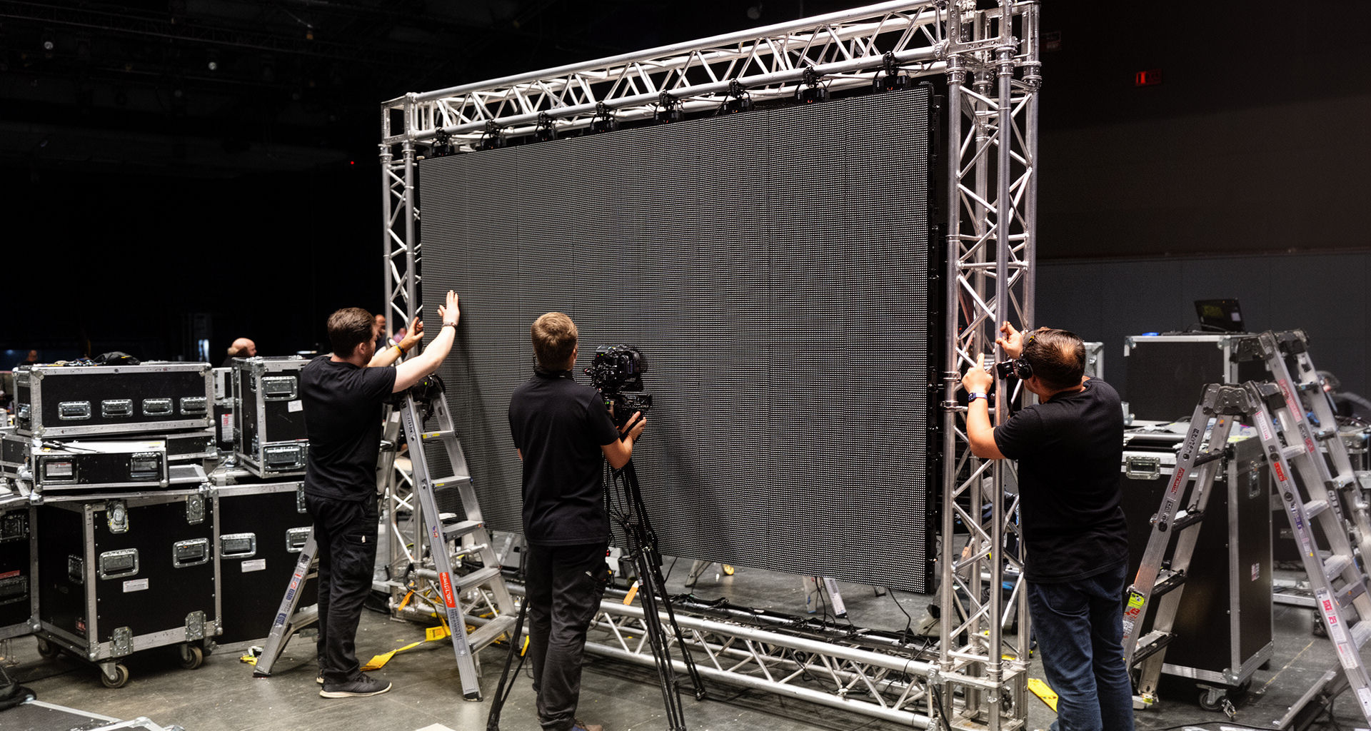 Crew assembling modular LED wall panels on truss during a NYC load-in