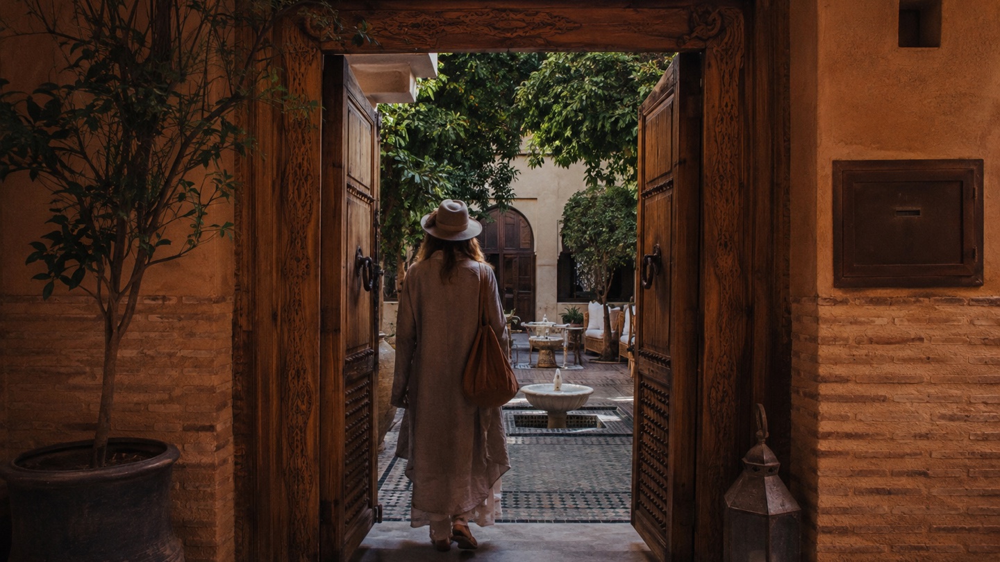 Traveler entering an ochre riad courtyard in Marrakech