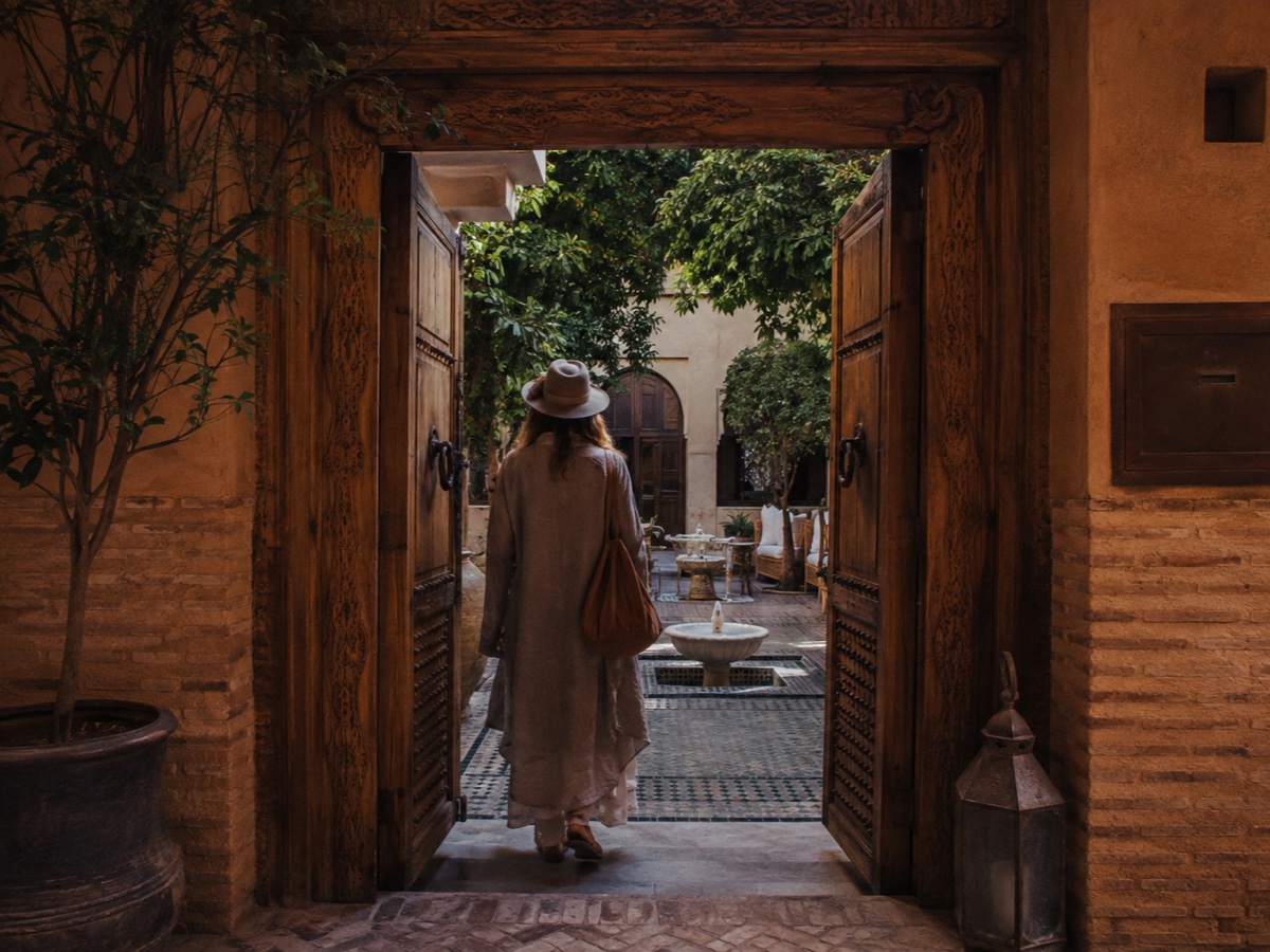 Traveler entering an ochre riad courtyard in Marrakech